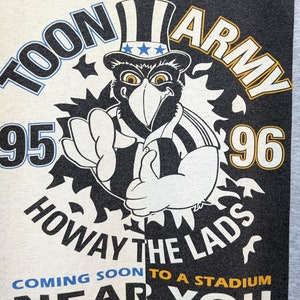 Puede incluir: Una camiseta gr&aacute;fica en blanco y negro con un p&aacute;jaro de dibujos animados que lleva un sombrero con estrellas y rayas. El texto de la camiseta dice "Newcastle's Toon Army 95-96 Howay The Lads Coming Soon To A Stadium Near You".