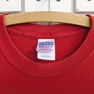 May include: Red t-shirt with a white Gildan "Heavy Cotton" tag.