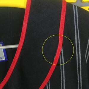 May include: Black and white striped shirt with red trim around the neckline. The shirt has a v-neck and is made of a soft, comfortable fabric.