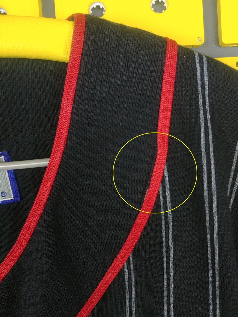 May include: Black and white striped shirt with red trim around the neckline. The shirt has a v-neck and is made of a soft, comfortable fabric.