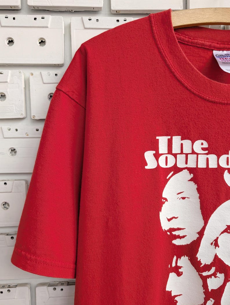May include: Red t-shirt with a white graphic of the band "The Sound" with four band members' faces.