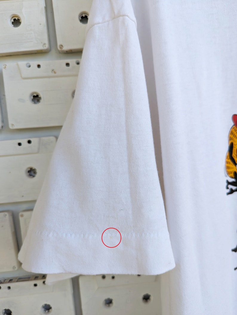 May include: White t-shirt with a small, light brown stain on the bottom of the sleeve.
