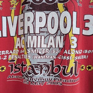 May include: Red t-shirt featuring the text "LIVERPOOL 3 AC MILAN 3" with player names and the word "istanbul". The shirt also includes the date "25 May 2005" and star graphics.
