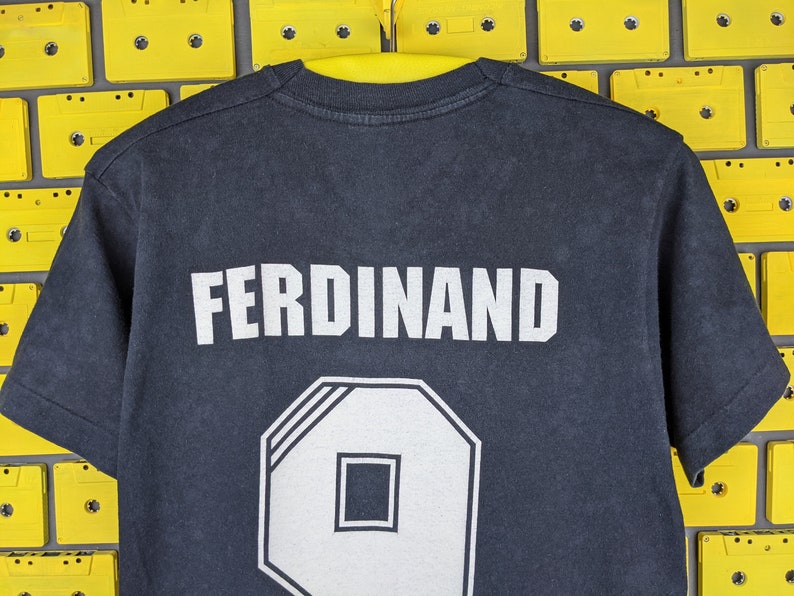 May include: Black t-shirt with white text that reads "FERDINAND" and a white number "9" on the back.
