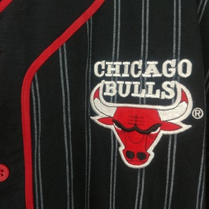 May include: Black and white striped baseball jersey with a red embroidered Chicago Bulls logo featuring a red bull with white horns and a registered trademark symbol.