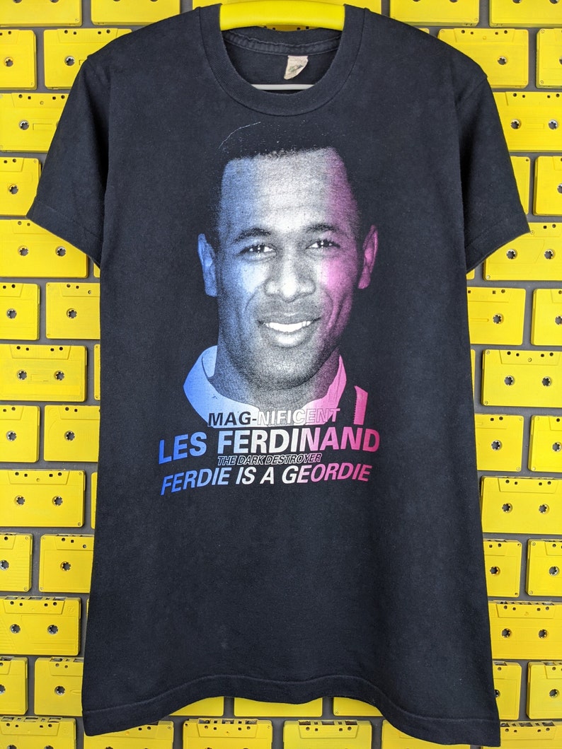 May include: Black t-shirt with a photo of Les Ferdinand, a soccer player, and the text "MAGNIFICENT LES FERDINAND THE DARK DESTROYER FERDIE IS A GEORDIE".