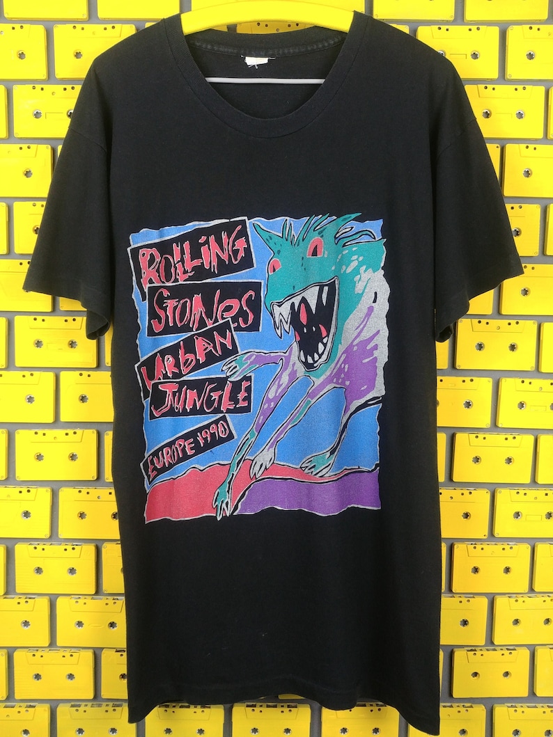 May include: Black t-shirt with a colorful graphic of a cartoon monster and the text "Rolling Stones Urban Jungle Europe 1990".
