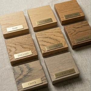 Finish samples in 8 colours, each labeled with a brass name plate. Raw, Natural, Light Oak, English, Antique, Dark Oak, Onyx and Belgium Grey.