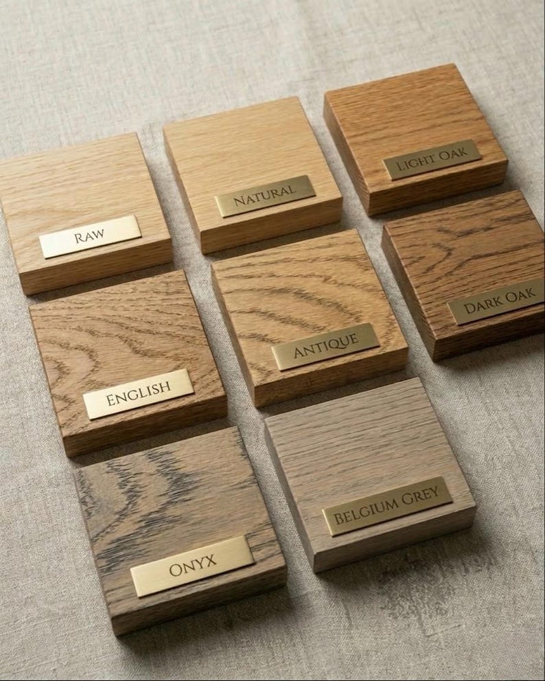 Finish samples in 8 colours, each labeled with a brass name plate. Raw, Natural, Light Oak, English, Antique, Dark Oak, Onyx and Belgium Grey.