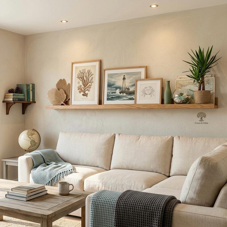 extra long oak picture shelf in a cozy modern living room. with white fabric sofa coastal art work on the shelf.