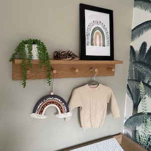 oak peg shelf in a Childs room with cloths hook and nursery decor on the shelf.