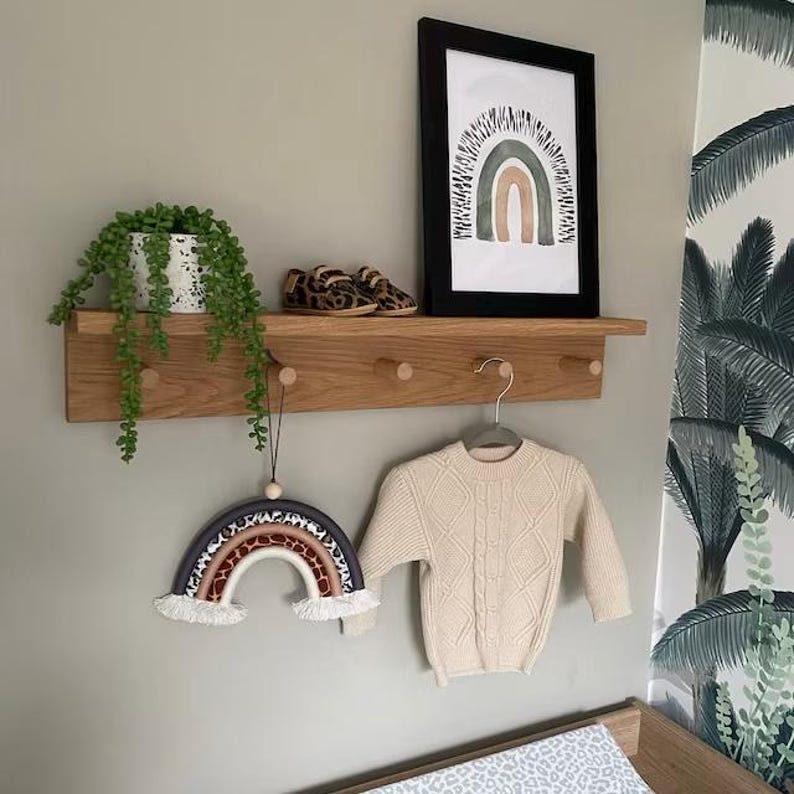 oak peg shelf in a Childs room with cloths hook and nursery decor on the shelf.