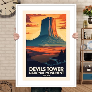 May include: A vintage-style poster featuring an illustration of Devils Tower National Monument in Wyoming. The poster depicts a sunset sky with orange, yellow, and red tones. The text on the poster reads "Devils Tower National Monument, Est. 1906."