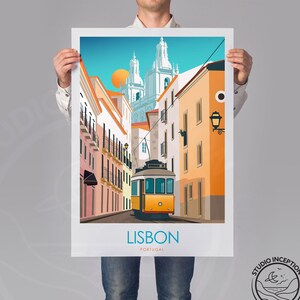 Peut inclure: Une illustration color&eacute;e d'une sc&egrave;ne de rue &agrave; Lisbonne, au Portugal. L'image repr&eacute;sente un tramway jaune qui monte une colline bord&eacute;e de b&acirc;timents color&eacute;s. Le texte "LISBON PORTUGAL" est en bas de l'image.