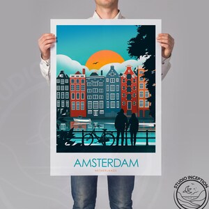 May include: A colorful illustration of Amsterdam, Netherlands, with a couple standing on a bridge overlooking a canal. The cityscape features traditional canal houses with red brick facades and a bright orange sunset in the background. The text "AMSTERDAM" and "NETHERLANDS" is displayed below the illustration.