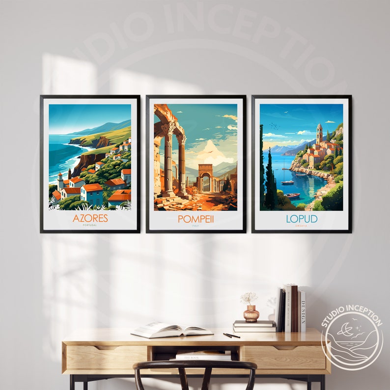 May include: Three framed travel posters with colorful illustrations of different locations. The posters are hung on a white wall above a wooden desk. The posters feature the words "AZORES", "POMPEII", and "LOPU&ETH;".