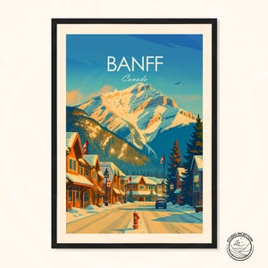 Puede incluir: Un p&oacute;ster de viaje enmarcado que muestra una escena callejera nevada en Banff, Canad&aacute;. La ilustraci&oacute;n representa un gran pico monta&ntilde;oso nevado bajo un cielo azul, con edificios de madera, pinos, una boca de incendios roja y banderas canadienses.