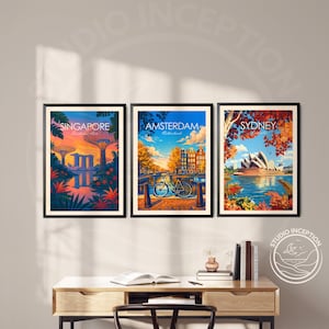 May include: Three framed travel art prints featuring Singapore, Amsterdam, and Sydney. The Singapore print shows a sunset over the city's gardens. The Amsterdam print depicts a bicycle on a bridge. The Sydney print shows the Opera House.