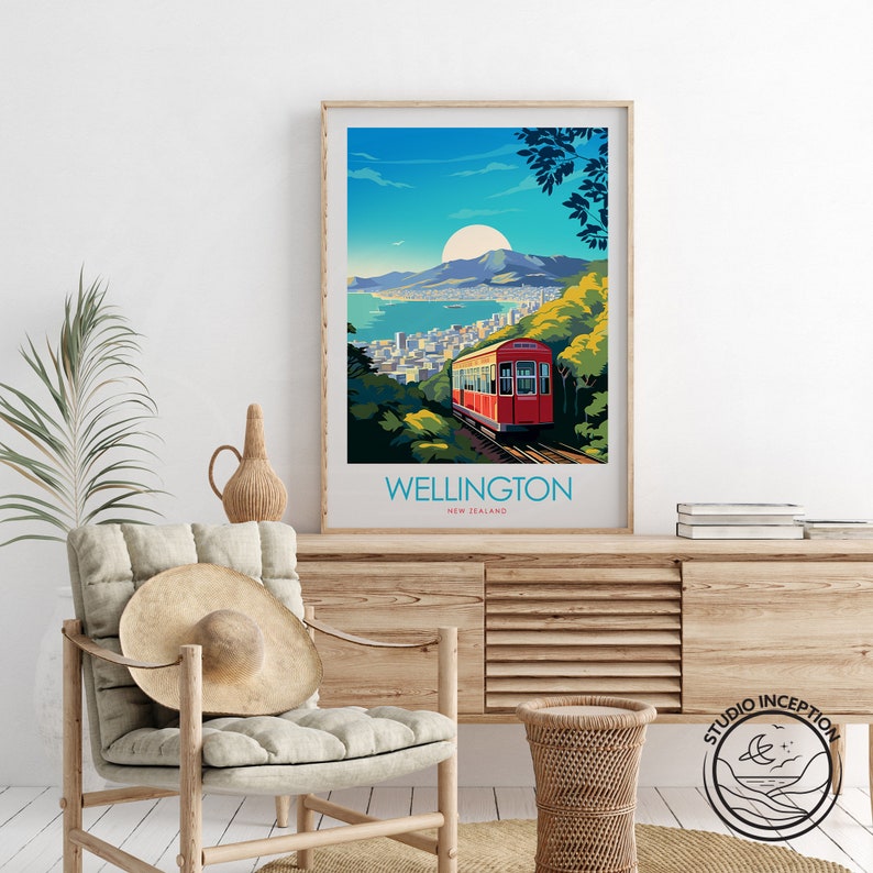 Może przedstawiać: Oprawiony wydruk artystyczny przedstawiający stylizowaną ilustrację Wellington w Nowej Zelandii. Grafika przedstawia czerwony wagonik kolejki linowej, krajobraz miejski i duże słońce na tle błękitnego nieba. Słowo "WELLINGTON" jest wydrukowane na dole.
