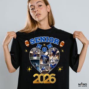 Pode incluir: Camiseta preta com um design com o texto "SENIOR MOM" e o ano "2026" em dourado. Uma colagem em forma de cora&ccedil;&atilde;o de jogadores de futebol americano est&aacute; no centro, com bolas e estrelas.