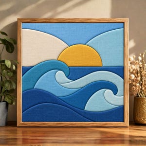 May include: A square wall art piece featuring a layered fabric design of a stylized ocean scene. The composition includes a bright yellow sun rising over rolling waves in shades of dark blue, medium blue, and light blue, all set in a wooden frame.