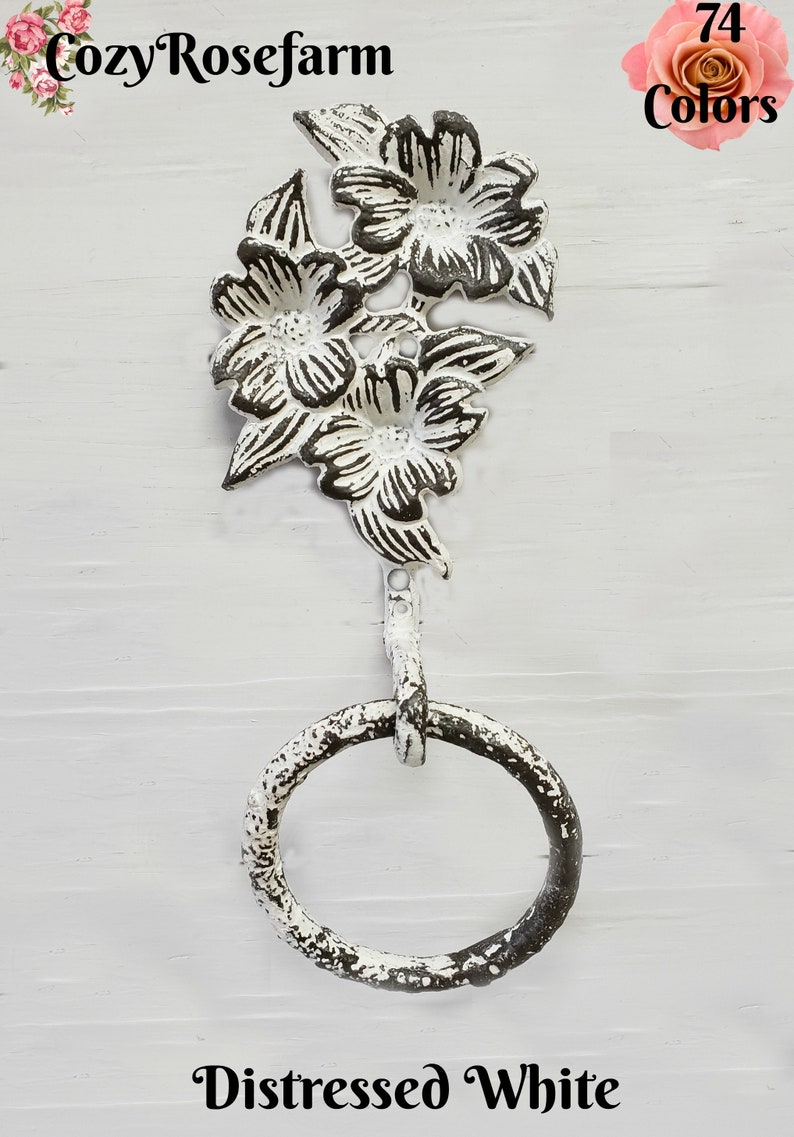 May include: Distressed white metal towel ring with a floral design. The top features three flowers and leaves. The ring is attached to the floral design by a small metal rod. The text "CozyRosefarm" and "74 Colors" are visible.