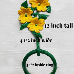 May include: A decorative wall-mounted towel ring with three yellow marigold flowers and green leaves. The towel ring is 30.5 cm tall, 11.4 cm wide, and has an 8.9 cm inside ring. The text "Cozy Rose Farm" and "74 Colors" are visible.