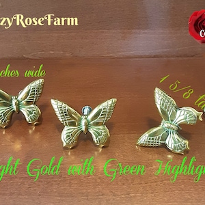 May include: Three bright gold butterfly-shaped decorative objects with green highlights. The butterflies are 2 inches wide and 1 5/8 inches tall. The image also includes the text "Cozy Rose Farm", "74 Colors", and "Bright Gold with Green Highlights".