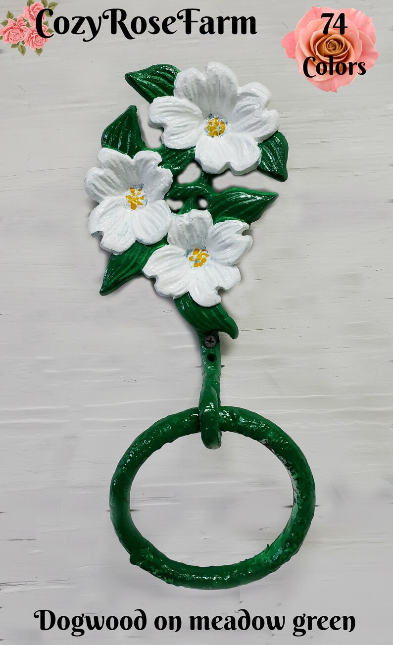 May include: A green dogwood flower towel ring with white flowers and yellow centers. The leaves are green, and the ring is also green. The text "Dogwood on meadow green" is at the bottom.