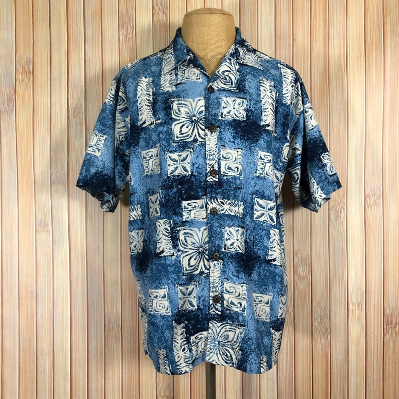 May include: A blue and white patterned short-sleeved button-up shirt with a traditional Hawaiian design.
