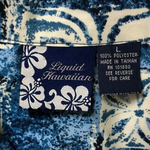 May include: A blue and white patterned shirt with a tag that reads "Liquid Hawaiian" and "100% Polyester Made in Taiwan RN 101880 See Reverse for Care".