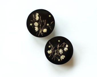 Vintage style furniture knob with dried spring flower Lily of the Valley on black background