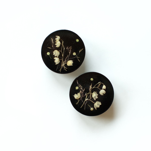 Vintage style furniture knob with dried spring flower Lily of the Valley on black background