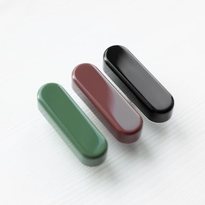 May include: Three small, rectangular, ceramic drawer pulls in green, brown, and black.