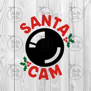 Op de afbeelding: Rood en zwart Santa Cam ontwerp met een hulsttak. Het woord "SANTA" staat in rode letters boven een zwarte cirkel met een witte camera lens. Het woord "CAM" staat in rode letters onder de cirkel.