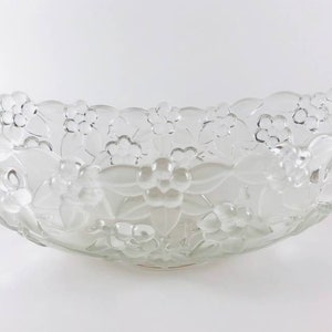 May include: A clear glass bowl with a floral design. The bowl is oval shaped and has a raised rim.