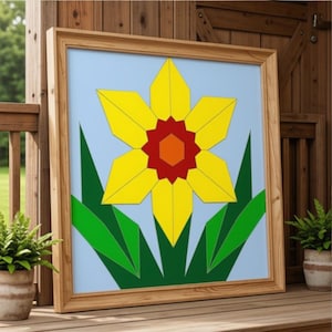 May include: A square framed wall art piece featuring a geometric illustration of a yellow daffodil with a red and orange center. The flower is set against a light blue background with sharp, angular green leaves extending from the base.