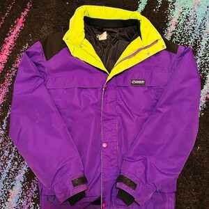 May include: A purple and black winter jacket with a neon green collar and accents. The jacket features a zip closure, two front pockets, and the brand name "BANFF". The cuffs have black velcro fastenings.