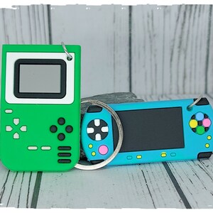 Portachiavi per console di gioco portatile verde turchese su una carta di supporto in una custodia di cellophane sigillata