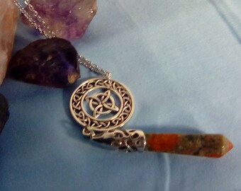 May include: Silver necklace with a Celtic knot pendant and a long, orange and green gemstone point.
