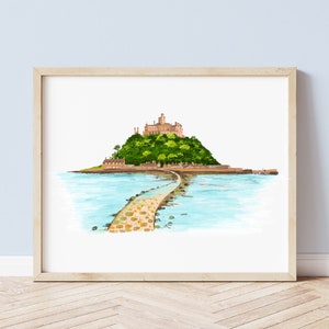 May include: Watercolor print of a castle on a small island connected to the mainland by a stone causeway. The castle is beige, atop a green, tree-covered hill. The water is light blue, and the print is framed in a light wood frame.