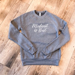 May include: Gray sweatshirt with the text "Midwest is Best" in white cursive lettering.