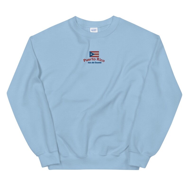 May include: Light blue sweatshirt with a small embroidered Puerto Rican flag and the text "Puerto Rico Isla del Encanto".