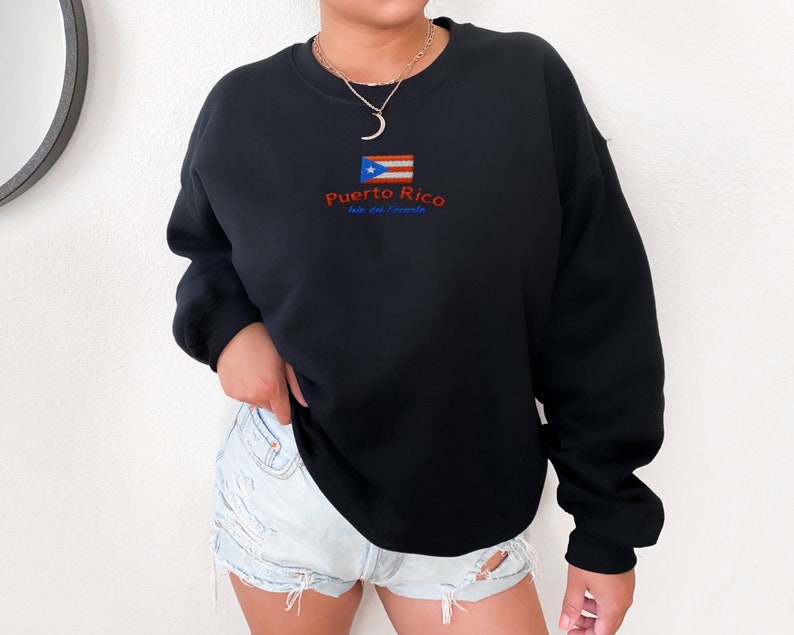May include: Black sweatshirt with a Puerto Rico flag and the text "Puerto Rico Isla del Encanto" embroidered on the front.