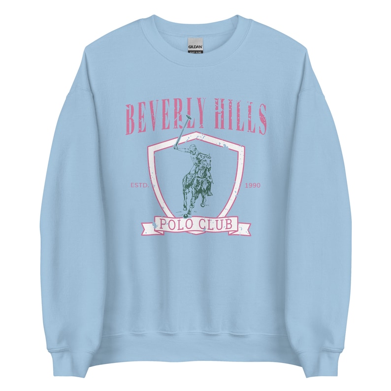May include: Light blue sweatshirt with a vintage-style graphic of a polo player on a horse. The graphic includes the text "Beverly Hills Polo Club" and the years "Est. 1990".