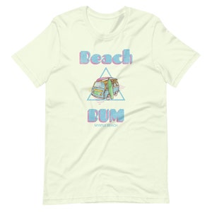 May include: A light green t-shirt with a retro-style graphic of a blue van with a surfboard on top. The text "Beach Bum" is in pink and blue letters with a pink and blue triangle behind the van. The text "Myrtle Beach" is in smaller black letters below the graphic.