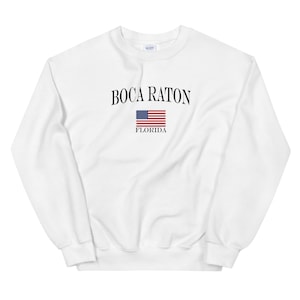 May include: White sweatshirt with black text that reads "Boca Raton, Florida" and a small American flag graphic.
