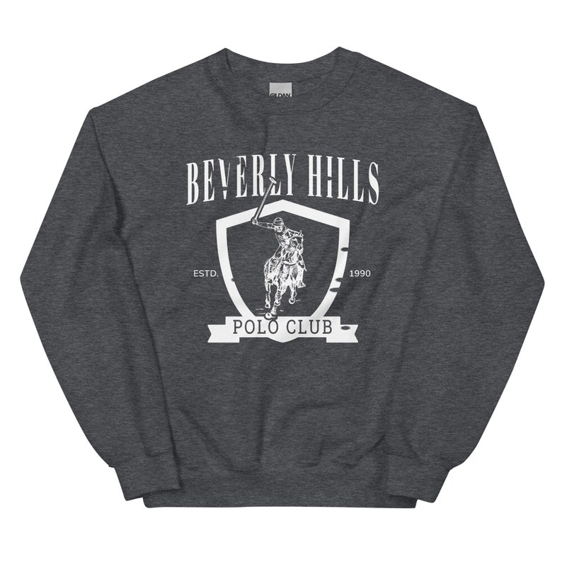 May include: A dark gray sweatshirt with a white graphic of a shield with a polo player riding a horse. The shield has the text "Beverly Hills Polo Club" and "Est. 1990".
