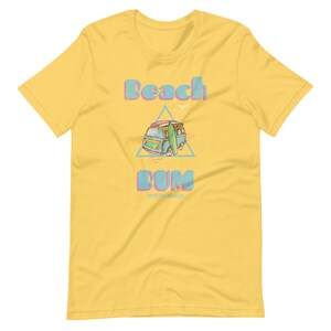 May include: Yellow t-shirt with a blue and pink graphic of a vintage van with a surfboard on top. The text "Beach Bum" is above the van and "Myrtle Beach" is below the van.