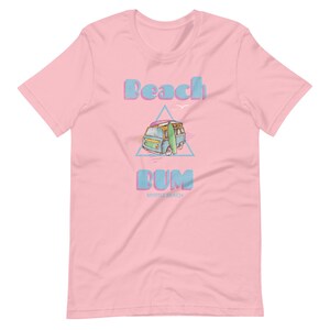 May include: Pink t-shirt with a blue and white vintage van with a surfboard on top. The text "Beach Bum Myrtle Beach" is printed on the shirt.